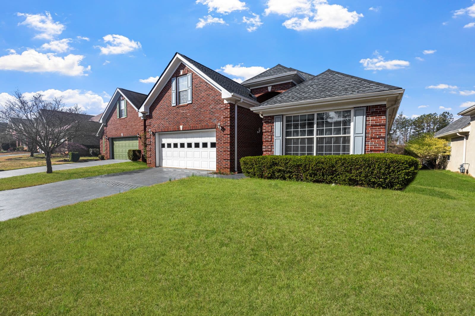 A red brick suburban home with a mown front lawn on a clear day